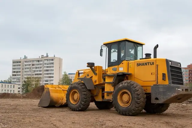 Фронтальный погрузчик с водителем работает на строительной площадке